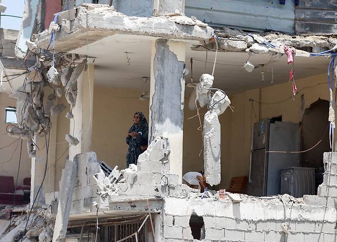 2024년 5월22일 이스라엘군의 폭격으로 무너진 팔레스타인 땅 가자지구 남부 칸유니스의 건물 안에서 한 여성이 망연히 밖을 바라보고 있다. REUTERS 연합뉴스