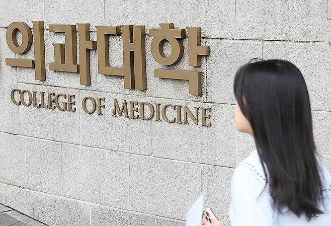 27년 만의 의대 입학정원 증원이 확정된 24일 시민들이 서울 시내 한 의과대학 인근을 지나고 있다. 한국대학교육협의회는 이날 대입전형위원회를 열고 각 대학이 제출한 2025학년도 대입전형 시행계획 변경 사항을 심의·확정했다. [연합]