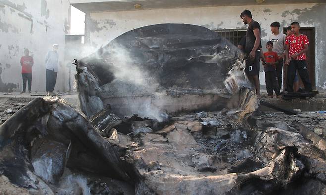 지난 22일(현지시간) 가자지구 남부 도시 라파의 지중해 연안에서 팔레스타인 주민들이 이스라엘의 공습으로 불에 탄 어선 잔해를 살피고 있다. 신화뉴시스