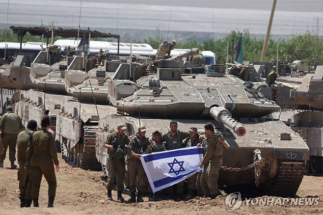 9일(현지시간) 가자지구 남단 미공개 위치에서 이스라엘 국기를 들고 사진찍는 군인들 [EPA 연합뉴스 자료사진. 재배포 및 DB 금지]