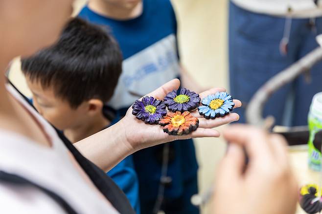 ‘한평공예’ 프로그램 참여자들이 커피 찌꺼기 반죽으로 완성한 꽃 모형을 들어 보이고 있다. 이수현 제공