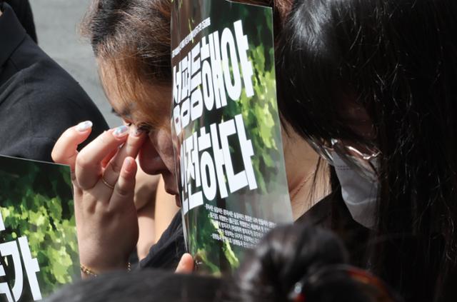 지난해 8월 24일 서울 관악구 등산로 성폭행 살인 사건 범죄 현장 인근에서 열린 피해자 추모집회에서 참가자가 눈물을 훔치고 있다. 연합뉴스