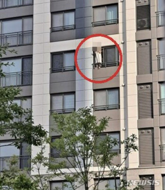 아파트 창틀에 서서 담배를 피우는 입주민. 온라인 커뮤니티 캡처