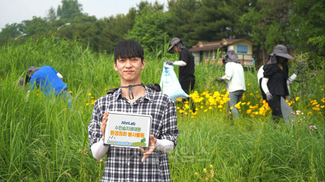 안랩 임직원들이 지난 24일 경기 성남 탄천 수진습지생태원에서 환경정화 봉사활동을 진행했다. 안랩 직원이 봉사활동 중에 사진을 찍고 있다. 안랩 제공