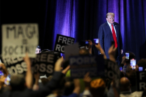 도널드 트럼프 전 대통령이 25일(현지시간) 워싱턴에서 열린 자유당 전당대회에서 연설하는 도중 자유당원들이 반대 피켓을 들고 있다. 로이터연합뉴스