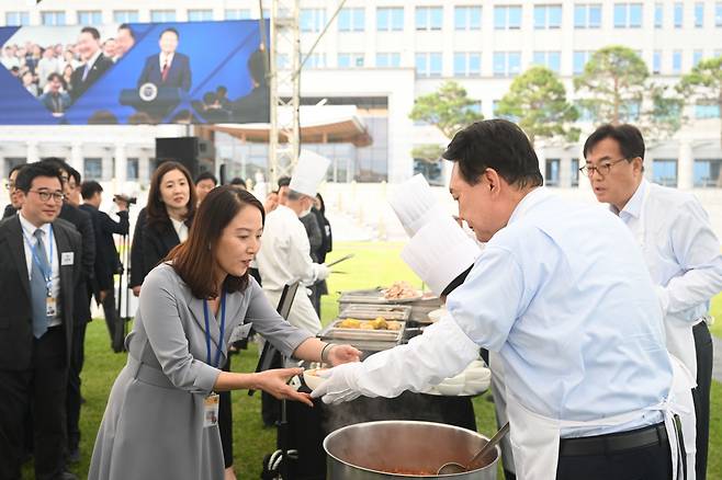 President Yoon Suk Yeol (right, front) hands out a Kimchi Jjigae bowl to a reporter at the front lawn of the presidential office in Seoul on Friday. (Presidential Office)
