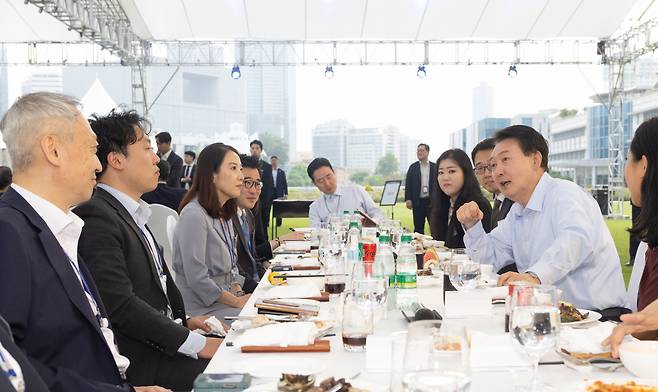 President Yoon Suk Yeol (second from right) speaks with reporters during dinner his office hosted at the presidential office's front lawn on Friday. (Presidential Office)