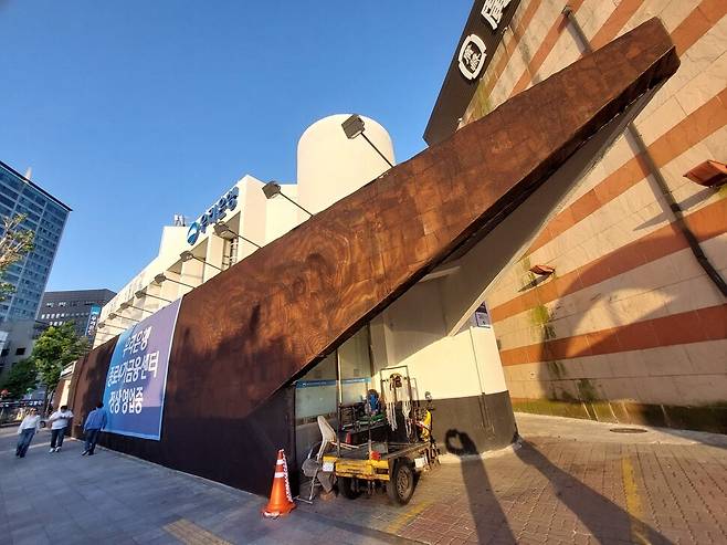 벽화가 암갈색 가림막으로 덮힌 우리은행 종로4가 금융센터 건물. 오른쪽 상단 사선 모양 벽체의 벽화 전돌 부분에서 표면이 벗겨지고 조각이 떨어지는 박락현상이 심화되고 있다. 가림막은 지난 1월 설치됐다. 노형석 기자