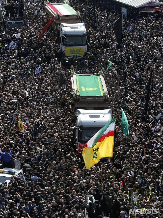 [테헤란=AP/뉴시스] 지난 22일(현지시각) 이란 수도 테헤란에서 열린 고 에브라힘 라이시 대통령과 헬기 추락 사고 희생자들의 장례식에서 시민들이 운구 차량을 따르고 있다. 2024.05.27.