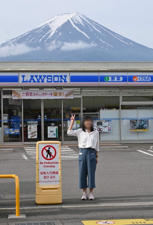 한 관광객이 21일 후지산이 보이는 야마나시현 가와구치코정의 편의점 앞에서 기념 촬영을 하고 있다. 가와구치코=AFP연합뉴스