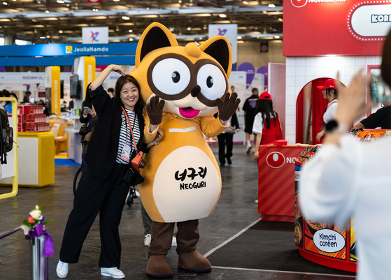 A visitor takes a picture with Nongshim’s raccoon dog character for Neoguri at the Korea Expo 2024 held at the Porte de Versailles exhibition hall in Paris, France. [TOGO COMMUNICATION]