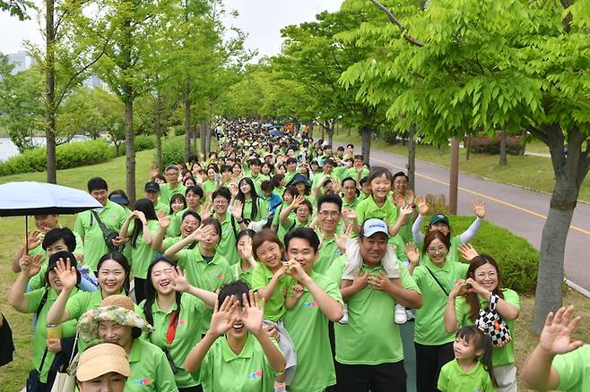 지난 26일 인천 청라 청라호수공원에서 열린 위러뷰유 걷기대회 참가자들이 호수 옆 산책로를 따라 손을 흔들며 즐겁게 걷고 있다. 위러브유 제공