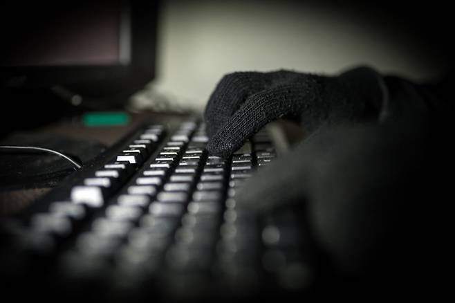 Fingers pressing on a computer keyboard in the dark .Silhouette black and white hands of anonymous hackers typing code on keyboard of laptop for remotely reach and receiving personal information online networking,