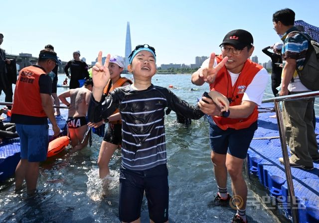 2일 서울 광진구 뚝섬한강공원에서 열린 제1회 쉬엄쉬엄 한강 3종 축제에서 수영 1km코스에 참여한 초등학교 6학년 한 학생이 완주 후 기념촬영을 하고 있다.