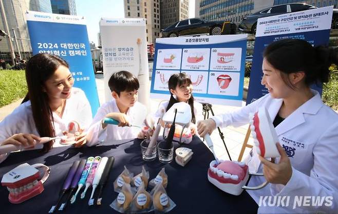 대한구강보건협회 김보미 홍보이사(오른쪽)가 어린이들에게 구강 모형과 음파전동칫솔을 활용해 치간과 잇몸선을 중심으로 양치하는 ‘표준잇몸양치법’을 교육하고, 아이들이 지도에 따라 연습하고 있다.