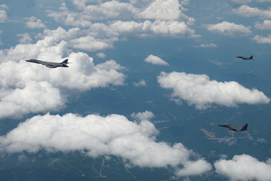 A U.S. B-1B supersonic strategic bomber, left, flies under escort from South Korean F-15K multirole fighters in the skies above the Korean Peninsula during a joint bombing drill held on Wednesday. [DEFENSE MINISTRY]