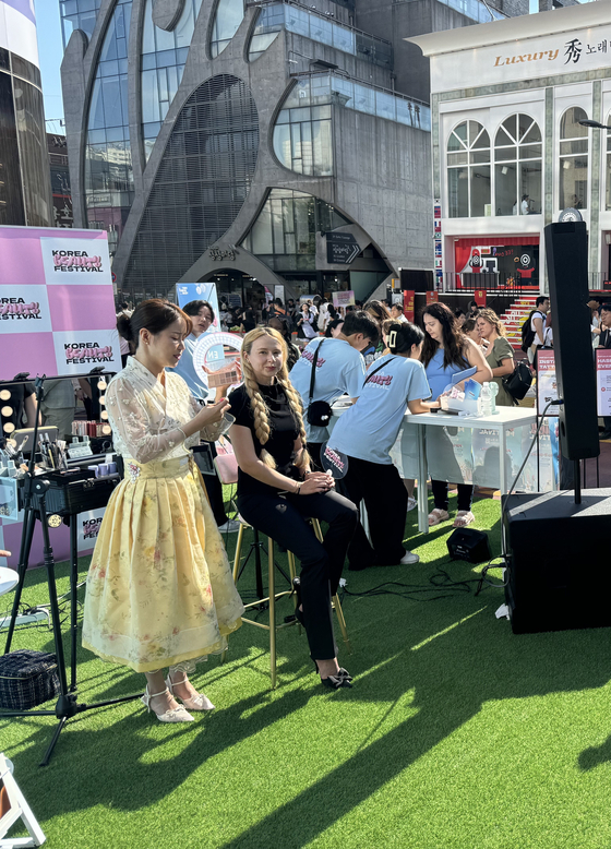 A makeup artist demonstrates a K-pop idol eye makeup look on the model at the Hongdae booth of the "2024 Korea Beauty Festival" in Mapo District, western Seoul, on Saturday. [KIM JI-YE]