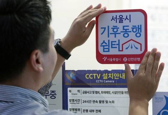 서울 중구 세종대로 신한은행 서울시청금융센터점에서 직원이 '기후동행쉼터' 현판을 부착하고 있다.  [뉴스1]