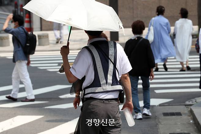 11일 서울 남대문시장 입구에서 한 교통안전요원이 양산과 얼음물을 든 채 근무하고 있다. 정지윤 선임기자