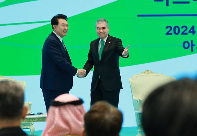 President Yoon Suk Yeol (left) and Turkmenistan's People's Council Chair Gurbanguly Berdymukhamedov shake hands at a business forum held in Ashgabat, Turkmenistan. (Yonhap)