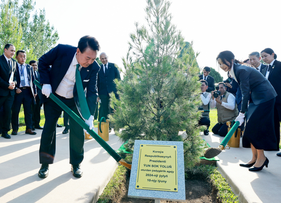 President Yoon Suk Yeol, left, and first lady Kim Keon Hee plant trees in a ceremony at a park near the Independence Monument in Ashgabat, Turkmenistan, during their state visit to the Central Asian country Monday. [JOINT PRESS CORPS]