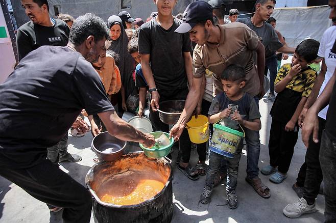 이스라엘과 하마스 간 팔레스타인 영토 분쟁이 계속되고 있는 가운데 13일(현지시간) 가자지구 북부 팔레스타인 난민 자발리아 캠프에서 사람들이 식량 지원을 받기 위해 줄을 서고 있다. [AFP]