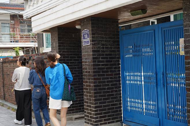 Visitors pass by the iconic blue gate of Seon-jae's house from "Lovely Runner" in Suwon, Gyeonggi Province on Tuesday. (Lee Si-jin/The Korea Herald)