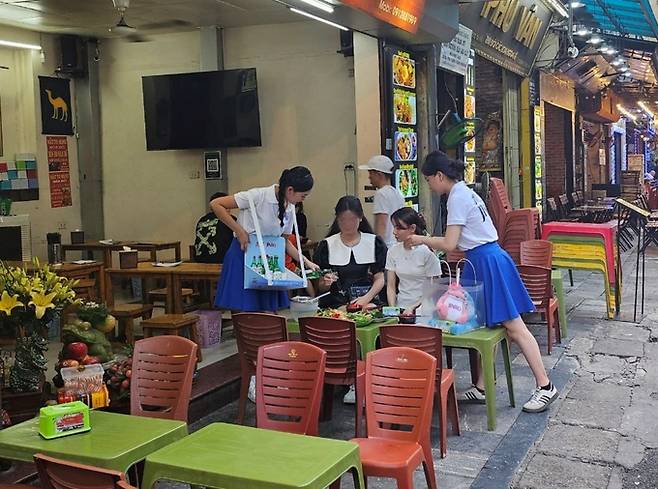 지난 10일(현지시간) 베트남 하노이 따히엔 맥주거리에서 하이트진로 판촉원들이 과일소주를 홍보하고 있다. 하이트진로 제공