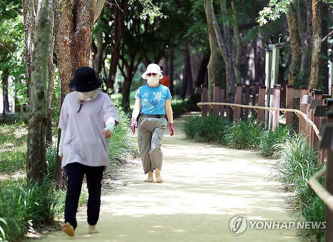 폭염에 모자·마스크 필수 (광주=연합뉴스) 천정인 기자 = 폭염주의보가 발효된 19일 광주 북구 시민의숲에서 시민들이 숲길을 따라 걷고 있다. 2024.6.19 iny@yna.co.kr