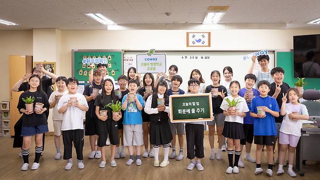 코웨이 임직원 봉사자들과 탑동초등학교 학생들이 '청정학교 교실숲 제6호' 조성 기념 단체 사진을 찍고 있다.