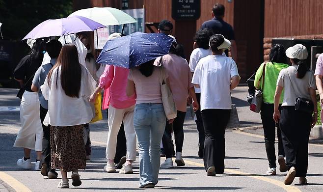 서울의 최고기온이 35도까지 오르며 올여름 첫 폭염주의보가 내려진 19일 오후 서울 남산에서 시민들이 양산과 모자 등으로 햇빛을 가리며 산책하고 있다. 2024.6.19. 뉴스1