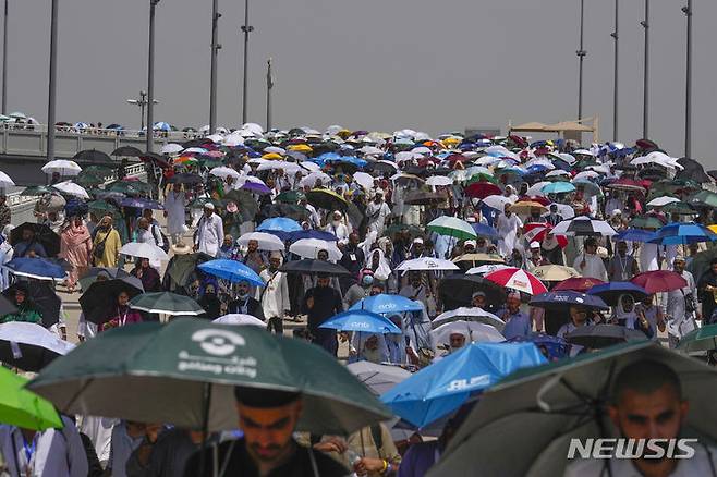 [메카(사우디아라비아)=AP/뉴시스]이슬람 순례객들이 지난 18일 사우디아라비아의 이슬람 성지 메카 인근 미나에서 뜨거운 태양볕을 가리기 위해 우산을 쓴 채 악마를 상징하는 기둥에 돌을 던지기 위해 몰려들고 있다. 모든 것들을 태워버릴 듯한 폭염으로 올해 사우디아라비아의 이슬람 성지 메카 순례객들 가운데 1000명이 넘는 사람들이 사망했다고 익명을 요구한 관리들이 23일 밝혔다. 2024.06.23.