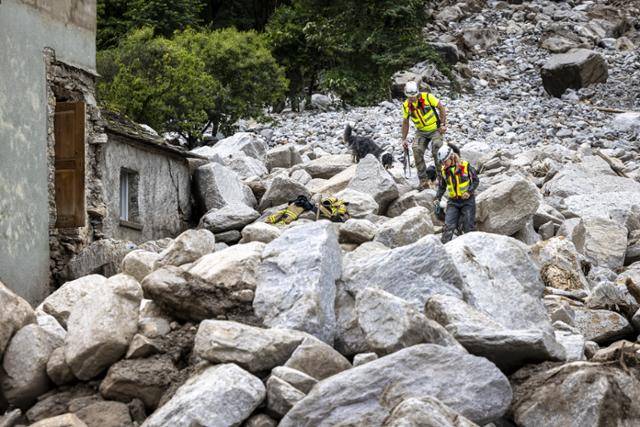 스위스 그라우덴주 로스탈로의 고산지대인 메솔치나 계곡에 집중호우로 홍수와 산사태가 발생해 인명 및 재산 피해가 속출한 가운데 23일 구조요원들이 수색견과 함께 현장을 수색하고 있다. 전날 발생한 홍수와 산사태로 1명이 사망했고, 2명이 실종상태며 수십 명의 주민들이 대피해야 했다. 스위스 기상청은 메솔치나 계곡에 124mm의 비가 내렸다고 밝혔다. 로스탈로=EPA 연합뉴스