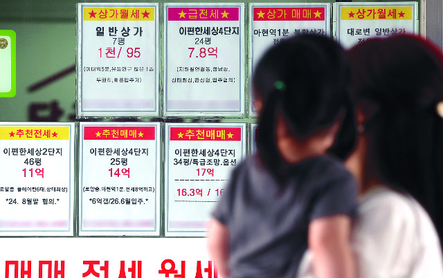 아이를 안은 시민이 23일 서울 한 부동산 상가 외벽에 게시된 매물 정보를 살펴보고 있다. 연합뉴스