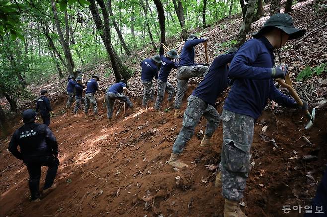 국방부 유해발굴감식단(왼쪽 검은 복장)과 9사단 장병들이 돌봉산 150고지에서 유해 발굴 작전을 펼치고 있다. 파주=박형기 기자 oneshot@donga.com