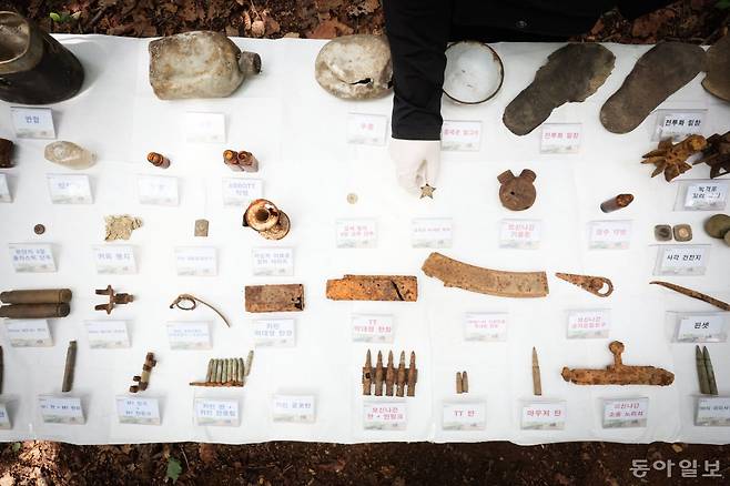 유해발굴감식단 오승래 발굴팀장이 유품을 정리하고 있다. 왼쪽 파란색으로 표시된 유품은 국군, 오른쪽 붉은색은 북한군과 중공군의 유품. 파주=박형기 기자 oneshot@donga.com