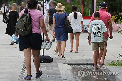 1년 중 낮이 가장 긴 절기상 하지이자 무더위가 계속된 지난 21일 오후 서울 광화문 광장에서 외국인들이 물에 발을 식히며 걷고 있다.  [연합뉴스]