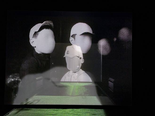 2층 다다미방 한쪽 전시실에서는 거장 오즈 야스지로 감독의 초창기 영화와 유명 만화가 요코야마 류이치의 전쟁선전용 만화영화가 각기 다른 스크린에서 영상이 겹쳐진 채 상영되는 기묘한 광경을 볼 수 있다. 오즈의 초기 대표작으로 꼽히는 1932년작 무성영화 ‘태어나기는 했지만’에 등장하는 아이들과 류이치의 선전만화영화 ‘잠수함의 후쿠짱’의 앳된 승조원 모습이 겹쳐진 채 상영되는 장면. 한결같이 얼굴에서 눈코입의 표정이 지워져 있어 섬뜩하고 기괴한 느낌을 안긴다. 노형석 기자