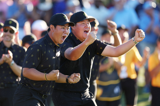 Korea's Tom Kim, left, and Im Sung-jae react to a putt on the 18th green by an International Team member during four-ball matches on day two of the 2022 Presidents Cup at Quail Hollow Country Club on September 23, 2022 in Charlotte, North Carolina. [GETTY IMAGES]