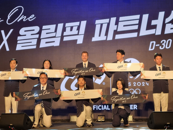 Oriental Brewery (OB) CEO Ben Verhaert, center in second row, poses for a photo at the brewer's media event announcing its official partnership with the Olympics on Wednesday at a hotel in eastern Seoul. Pictured from left in second row are Olympics medalists Yoo Nam-kyu, Kim Soo-nyung, CEO Verhaert, medalists Ha Tae-kwon and Cho Jun-ho. From center in the first row are medalist Kwak Yoon-gy and Seo Hye-yeon, senior vice-president of OB's marketing division. [YONHAP]