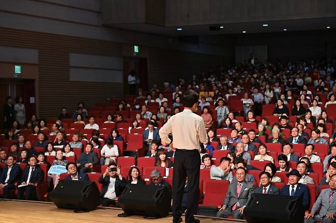 양복 상의를 벗고 셔츠 차림으로 단상에 서서 천안시민들의 질문에 답하며 대화하는 김태흠 충남 지사. 