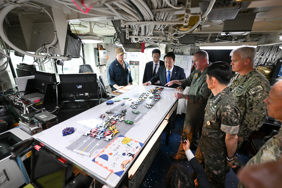 President Yoon Suk Yeol, center, listens to a briefing aboard the American nuclear-powered aircraft carrier USS Theodore Roosevelt (CVN-71), docked at a naval port in Busan on Tuesday.[PRESIDENTIAL OFFICE]