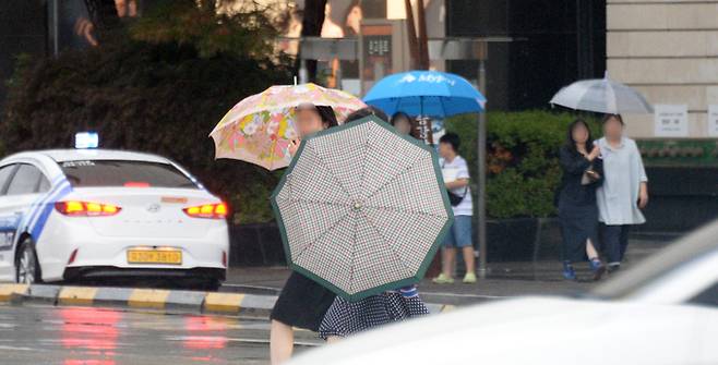 전북지역 곳곳에 호우주의보가 내려진 29일 전북 전주시 덕진구 백제대로에서 시민들이 우산으로 비를 피하며 길을 지나고 있다.    뉴시스