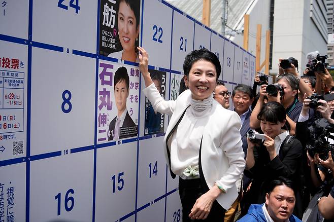 오는 7일 치러지는 일본 도쿄도지사 선거 후보 렌호가 지난달 20일 후보 포스터 게시판에 자신의 포스터를 부착하고 있다. /EPA 연합뉴스