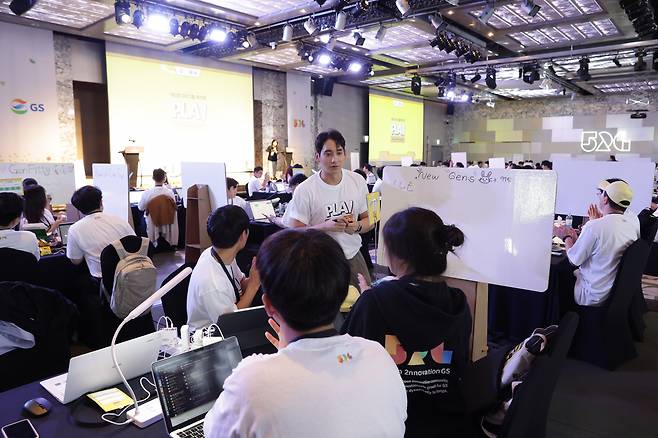 Hackathon participants discuss ideas for their projects with team members at a Seoul hotel on Wednesday. (GS Group)