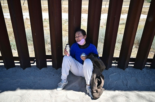 중국에서 온 불법이민자가 지난 6월 5일 캘리포니아 하쿰바의 국경 장벽에서 더위에 지쳐 물을 마시고 있다. 이날 조 바이든 미국 대통령은 대선을 앞두고 불법 이민자들에 대한 국경 장벽을 강화하는 조치를 실시했다. 하쿰바(캘리포니아) AFP 연합뉴스