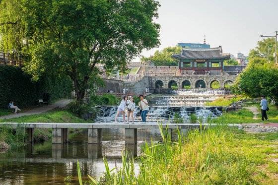 수원천과 화홍문을 배경으로 기념사진을 찍은 관광객들. ‘선재 업고 튀어’의 주 촬영지로 알려지며, 최근 방문객이 부쩍 늘었다.