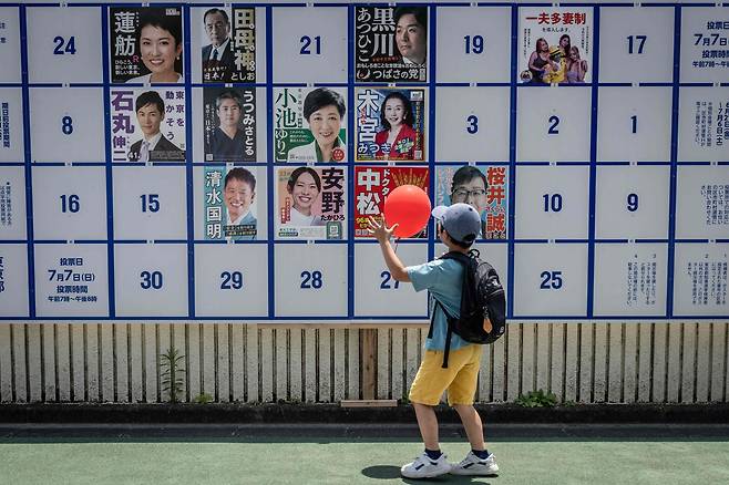 7일 일본 도쿄에서 열린 도쿄 도지사 선거 캠페인 포스터를 보고 있는 어린이. / AFP 연합뉴스