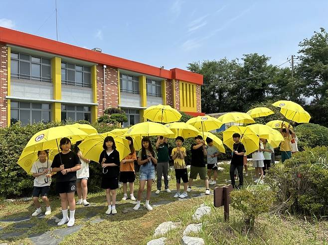 LG헬로비전은 지난 3일(수) 전북 부안남초등학교에서 '어린이가 만드는 기후동행학교' 프로그램을 진행했다. 사진은 학생들이 플라스틱으로 만들어진 안전우산을 들고 있는 모습.