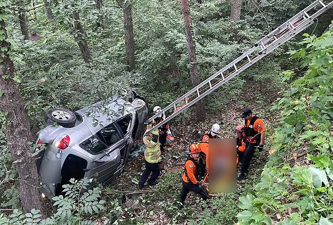 8일 오후 경남 양산시 원동면 한 왕복 2차선 도로를 달리던 SUV 차량이 3m 아래 산비탈로 추락한 가운데 소방대원들이 운전자를 구조하고 있다. 사진 경남소방본부